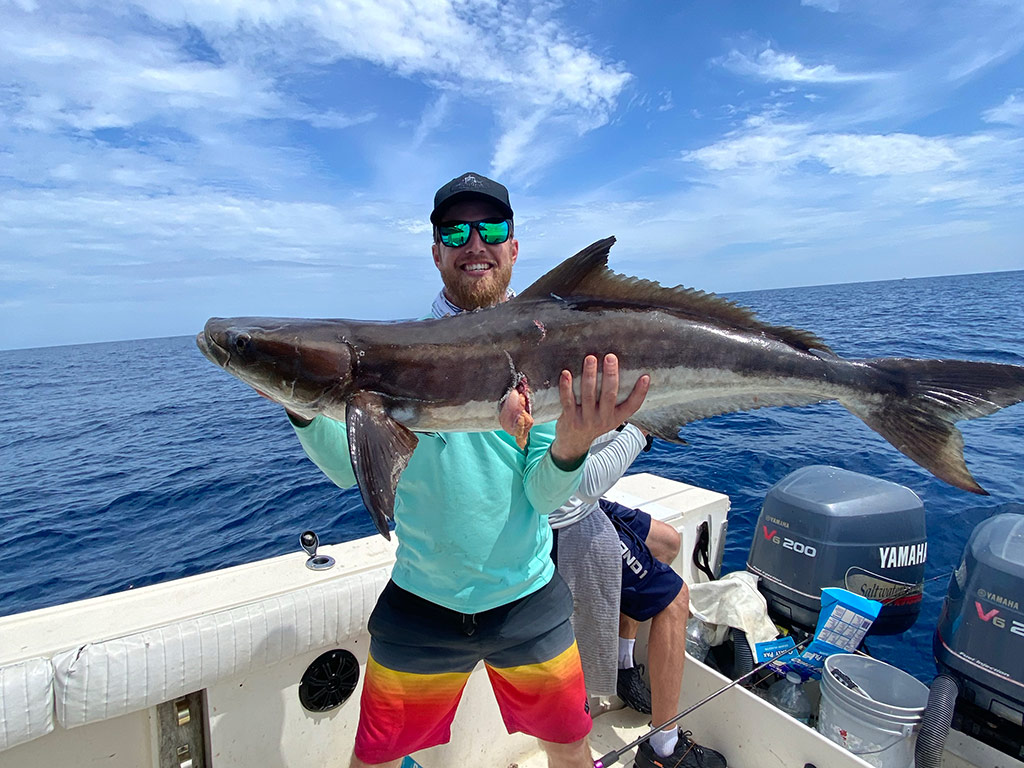 An angler holds a Cobia he caught during an offshore trip.