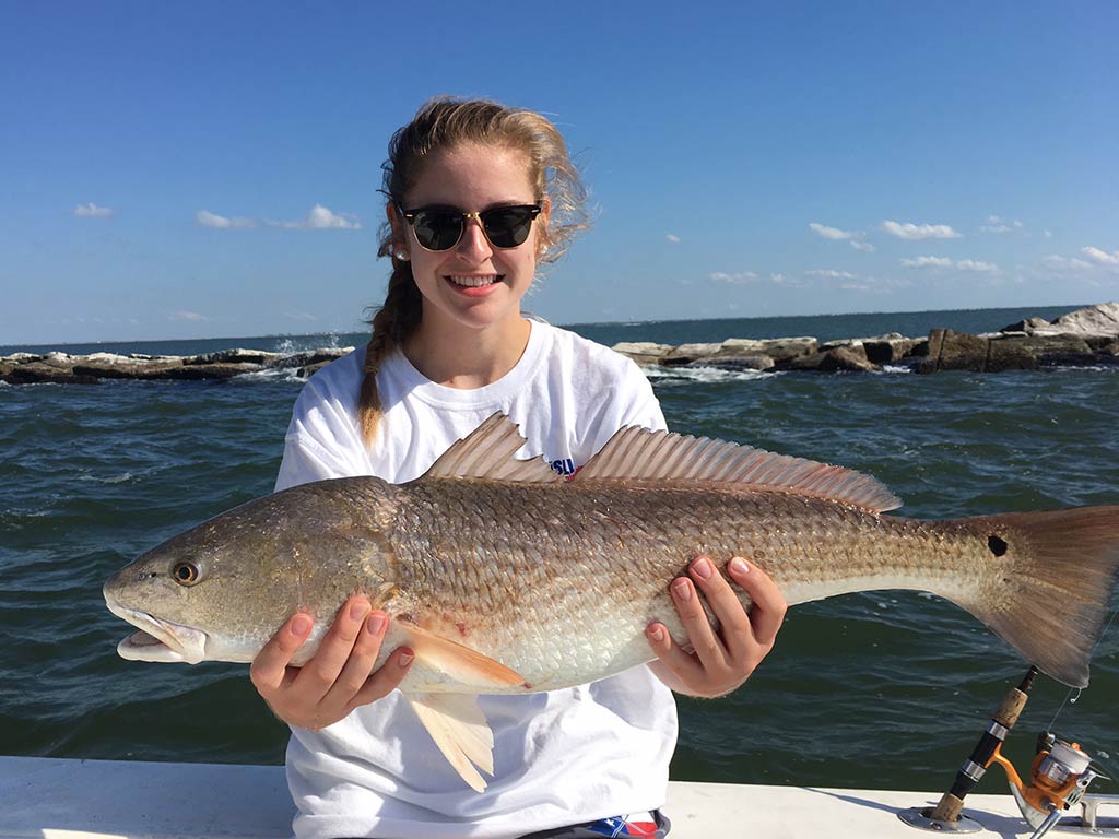 An angler holding a Redfish she recently caught fishing in Texan inshore waters.