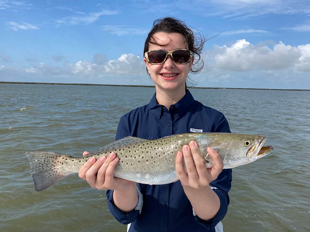 A smiling young angler holds a Speckled Trout she recently reeled in.