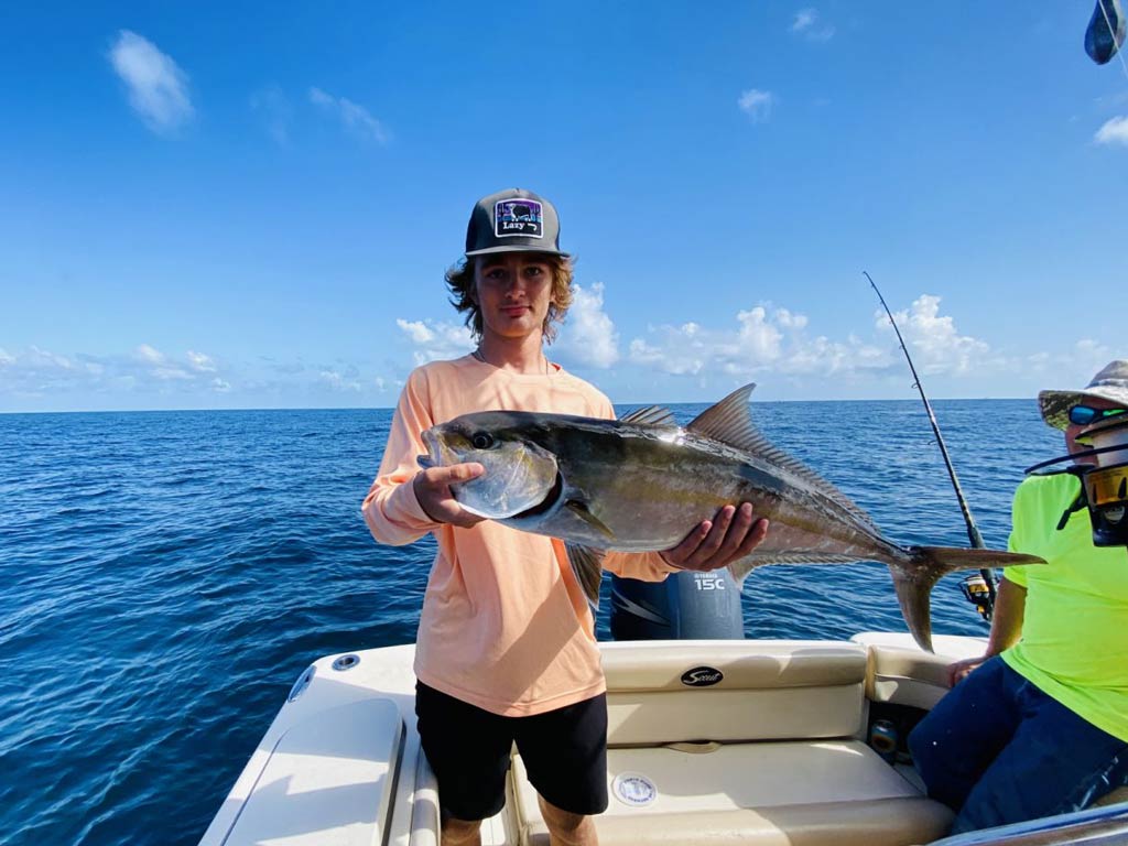 A teenager holding an Amberjack caught while deep sea fishing in Charleston