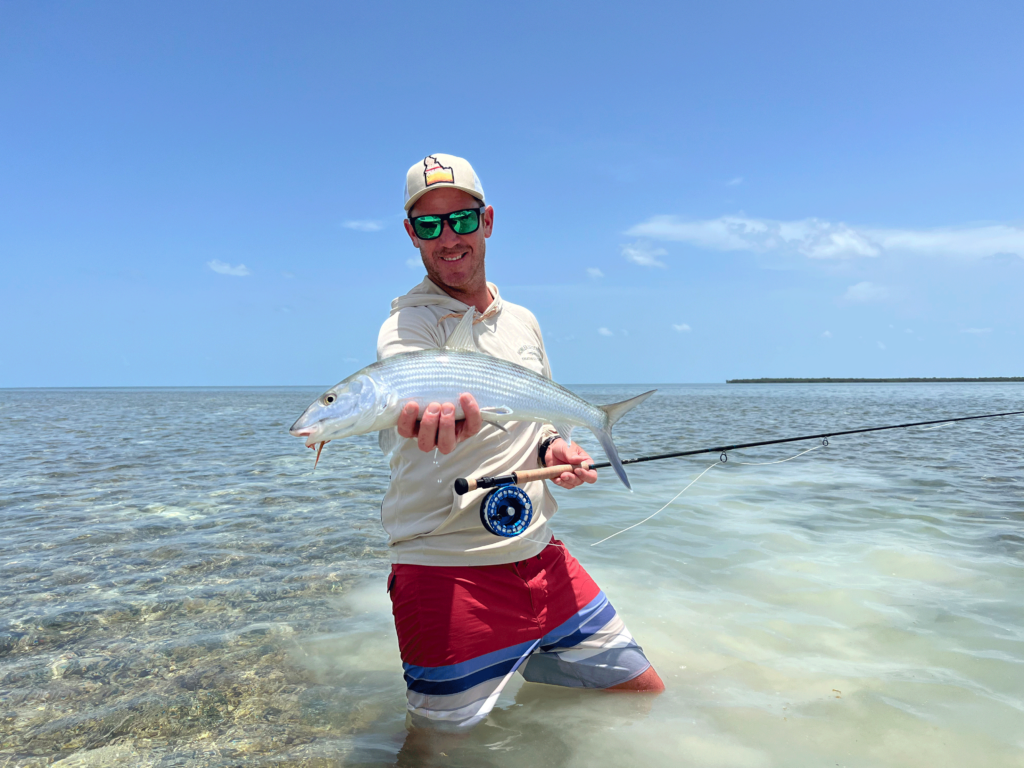 A smiling angler holding a freshly caught Bonefish while fly fishing in the Florida Keys.