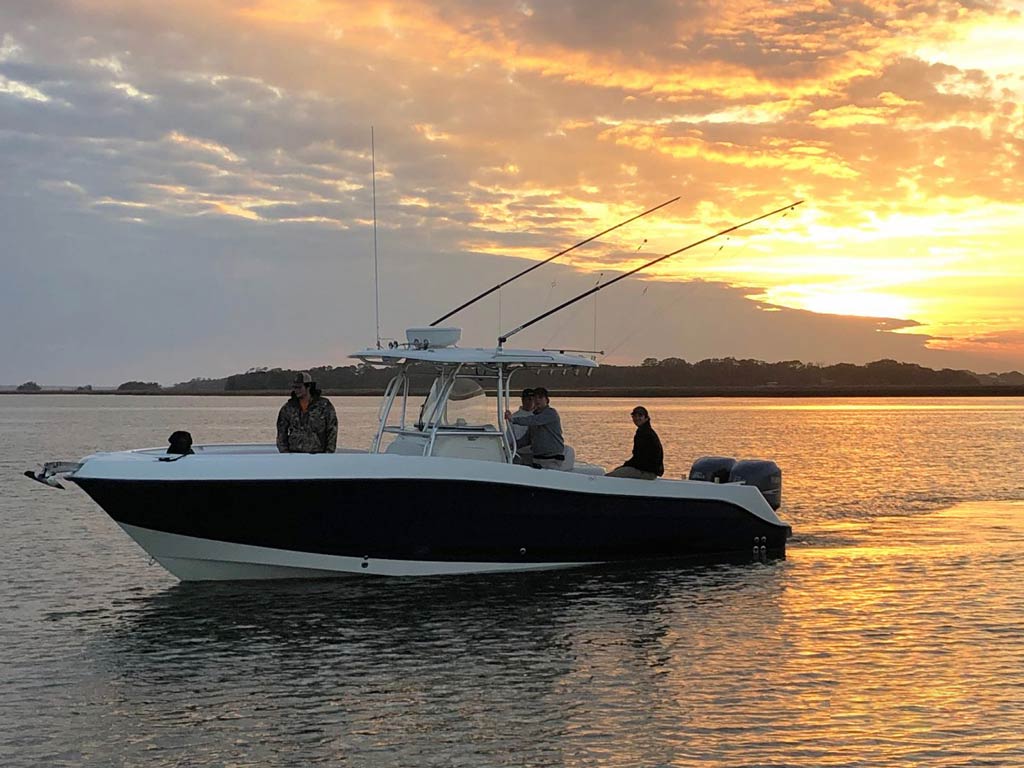 A sunset view of a Charleston charter fishing boat with its captain and a group of anglers on it