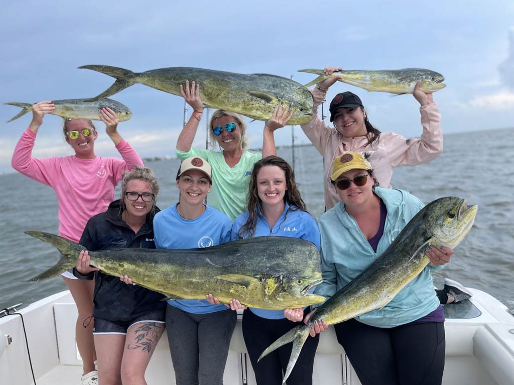 A group of anglers on a charter fishing boat holding Mahi Mahi caught while deep sea fishing in Charleston