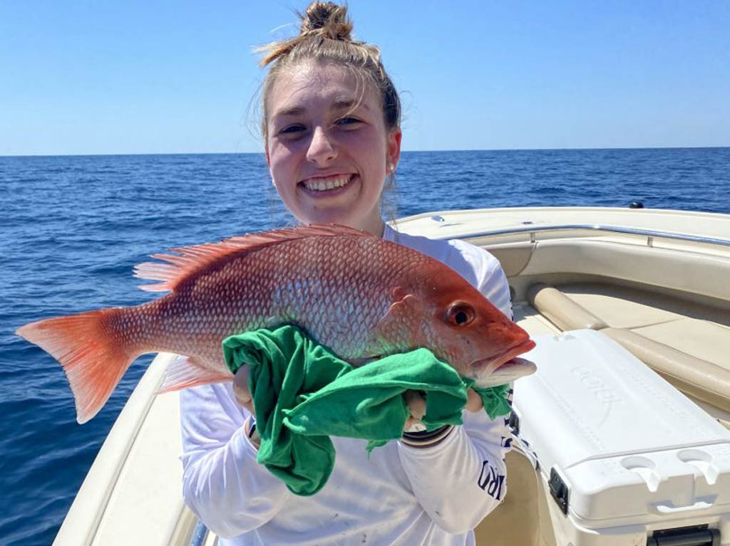 An angler holding a Red Snapper with both hands caught in Charleston