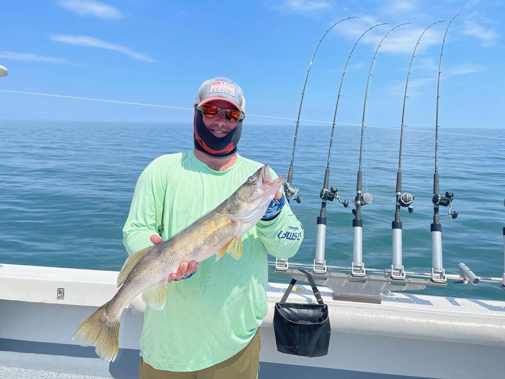 An angler posing with a Walleye he reeled in on a Lake Erie fishing charter.