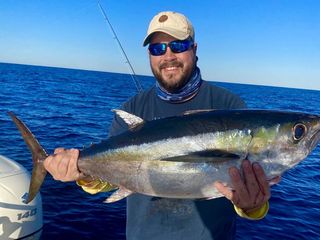 A happy angler holding a Yellowfin Tuna caught while deep sea fishing in Charleston