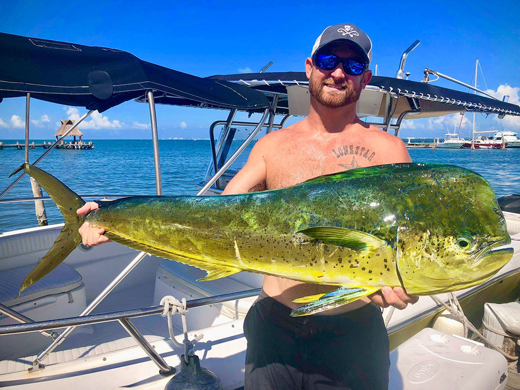 An angler holds up a Mahi Mahi he recently caught during an offshore trip out of Cancun.