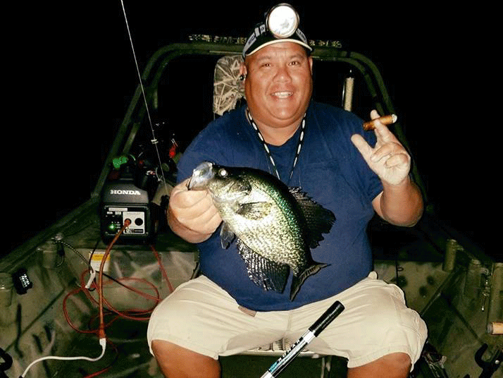 An angler on a boat fishing for Crappie (Speckled Perch) in Florida at night.