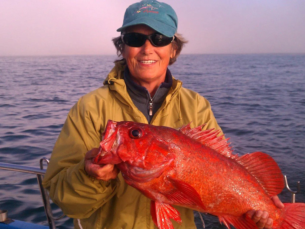 An angler holding a Rockfish she just caught on a deep sea trip.