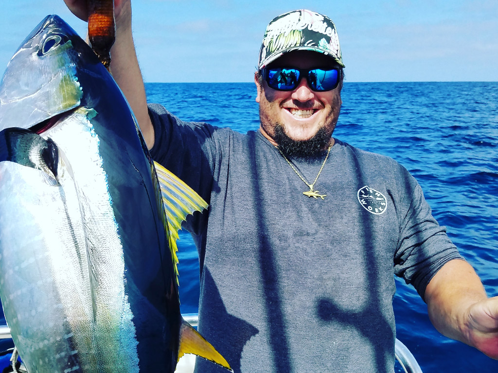 A smiling angler holds an Albacore Tuna he caught during a deep sea fishing trip out of San Francisco.