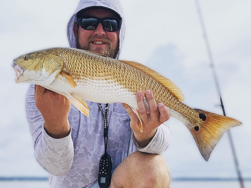 A happy angler holds a Red Drum he caught near Morehead City on a windy day.