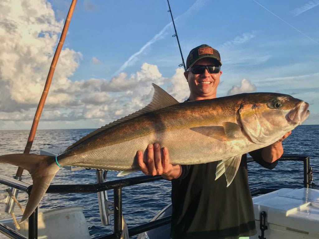 An angler holding a big Amberjack caught while fishing in Madeira Beach