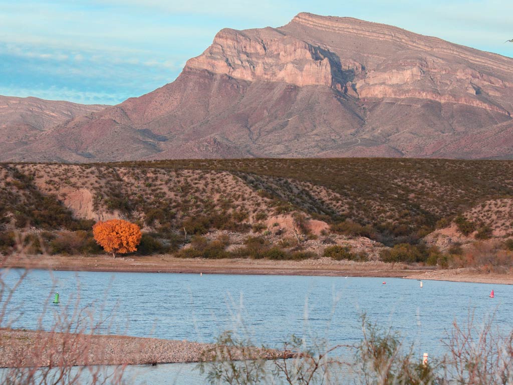 A scenic view of a mountain in the distance and Caballo Lake in New Mexico in front of it at sunset