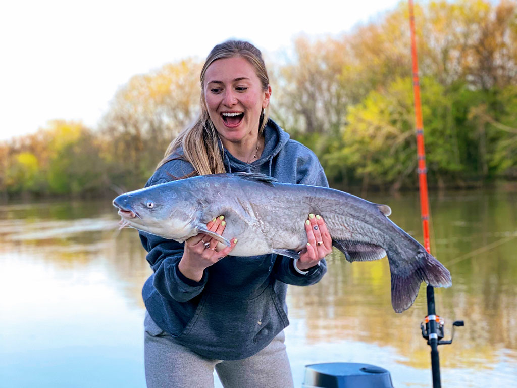 A female anglers stood on a boat holding a Catfish caught in North Carolina