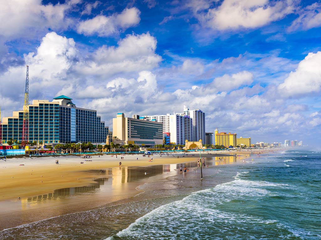 A view from the water of a sandy beach, buildings, clouds in the sky, and the ocean in Daytona Beach