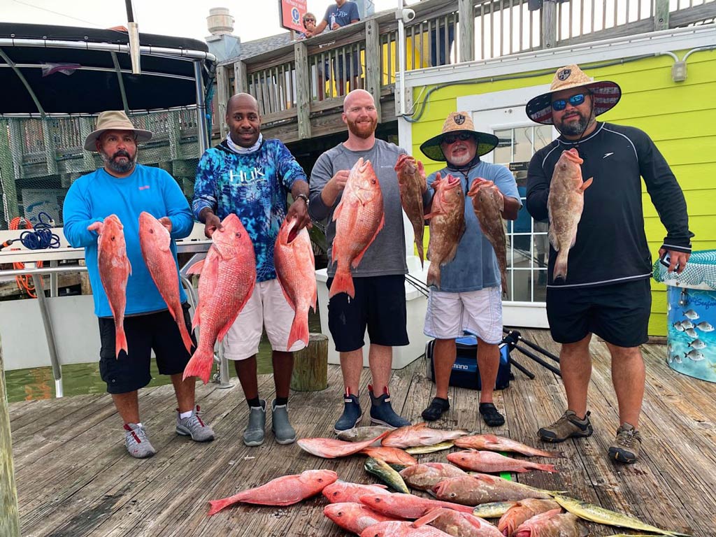 A group photo of anglers holding their catches while standing on a dock in the John’s Pass area in Madeira Beach