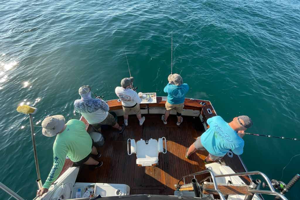 A view from above of five anglers standing on a charter boat and fishing on a sunny day