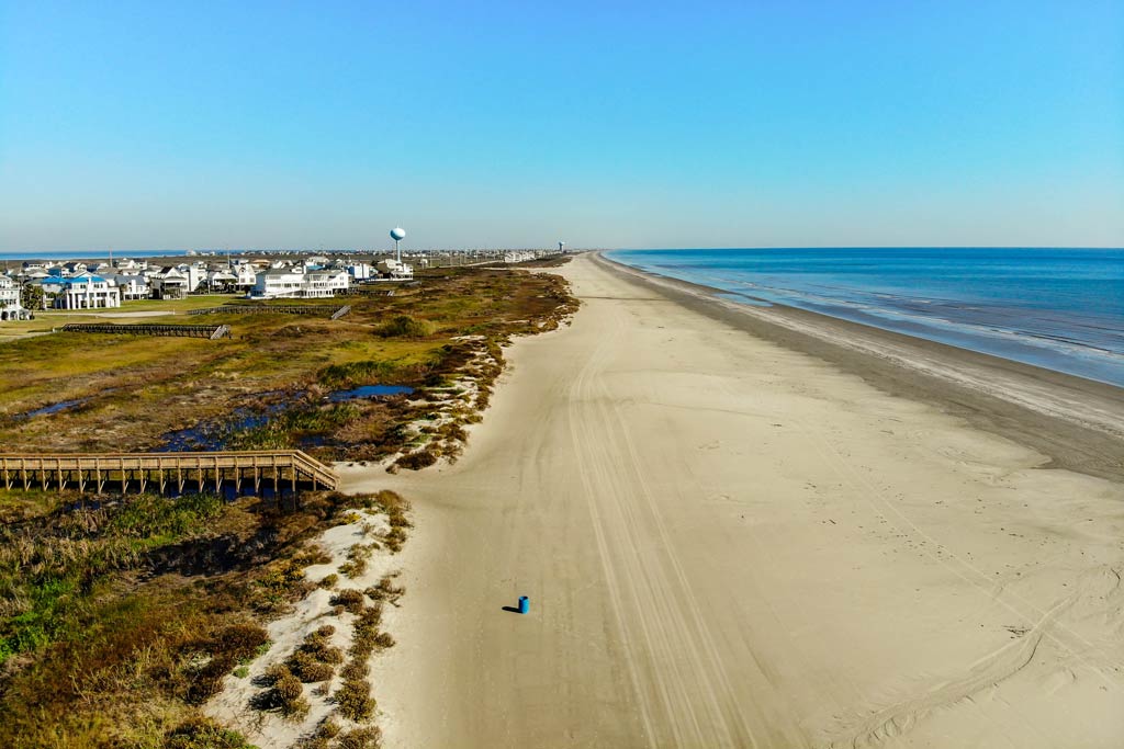 An aerial view of a quiet San Luis Pass Beach on a sunny day with the Gulf of Mexico on the right-hand side of the image