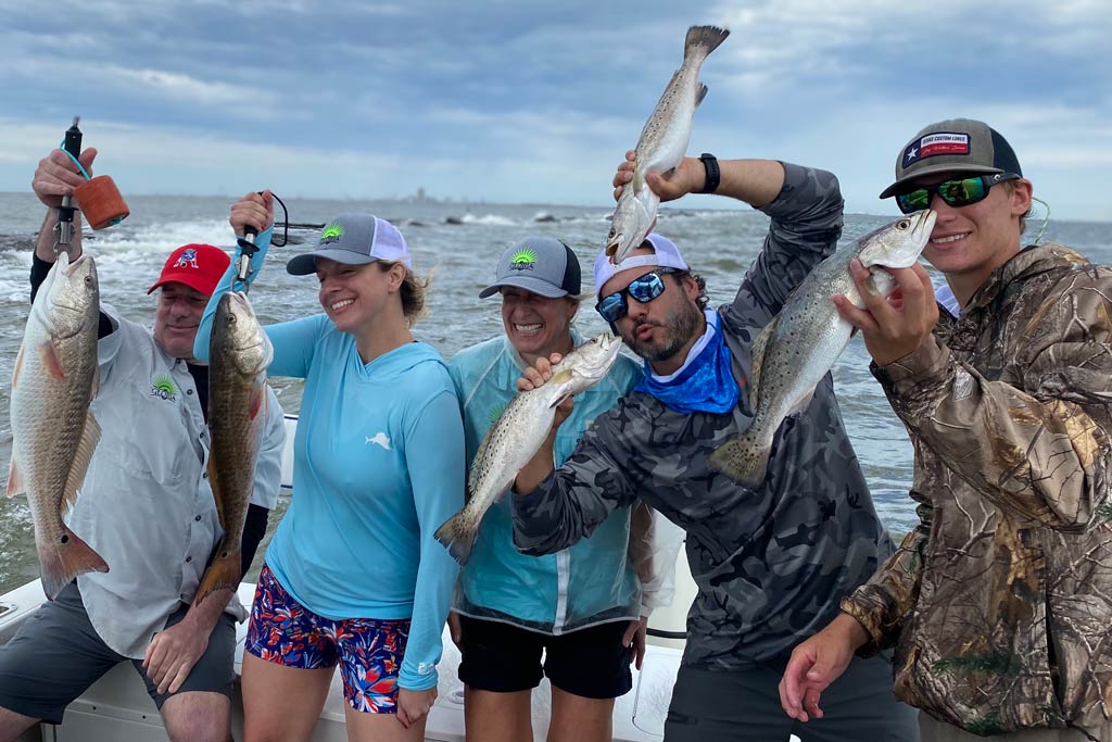 A group of anglers on a fishing boat, each holding a fish they caught in San Luis Pass