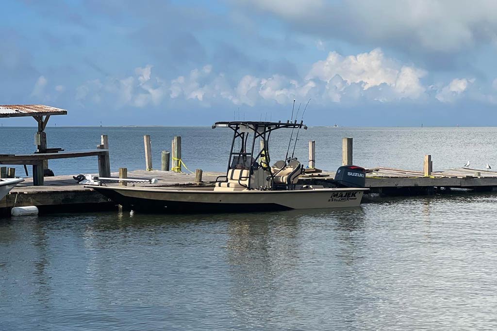 A center console charter boat at a dock on a cloudy day in San Luis Pass