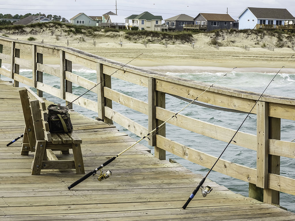 Three rods lined up against the side of a fishing pier in North Carolina on a cloudy day