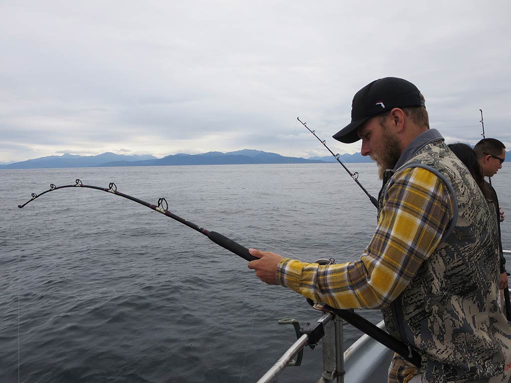 An angler attempts to reel in a Halibut from a fishing charter in Homer