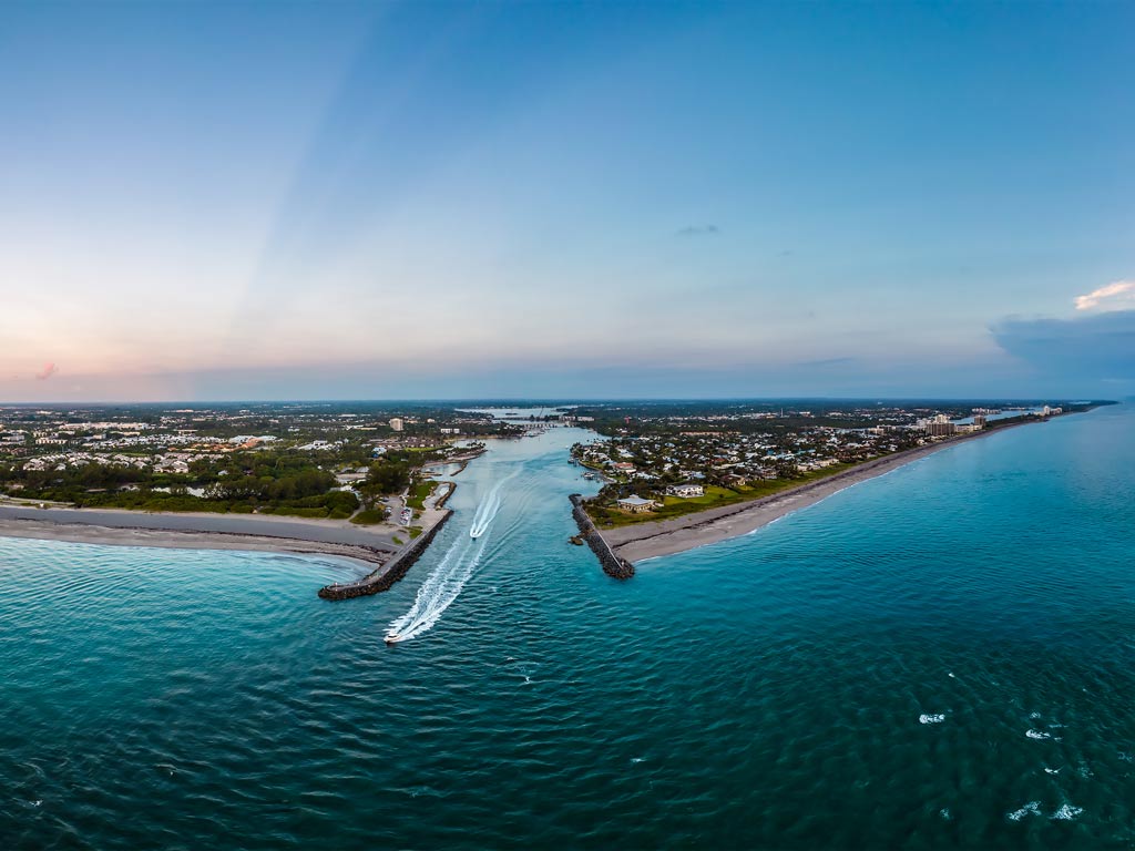 An epic aerial shot of the Jupiter Inlet and boats coming out of it.