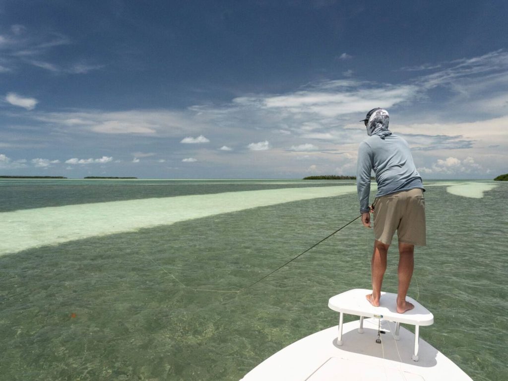 A fishing guide standing on the platform of a boat, fishing in the flats in Key West, Florida