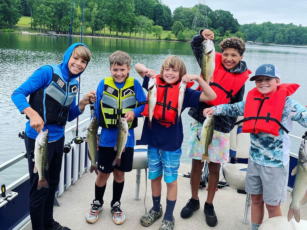 A group of children holding a Largemouth Bass each during North Carolina's Bass fishing season