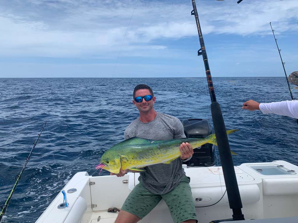 An angler on a charter boat, posing with a sizeable Mahi Mahi he caught.