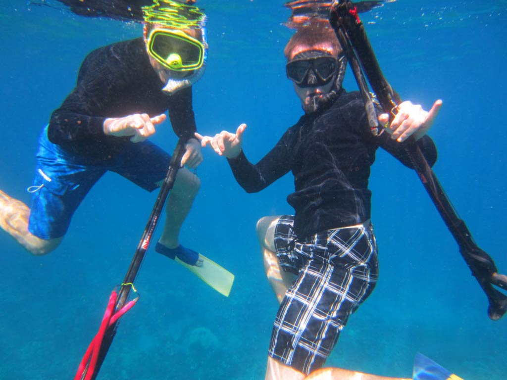 An underwater view of two spearos on a Maui spearfishing adventure.