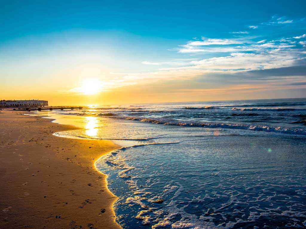 A sunrise, as seen from one of Ocean City's beaches with a pier on the left of the image. 
