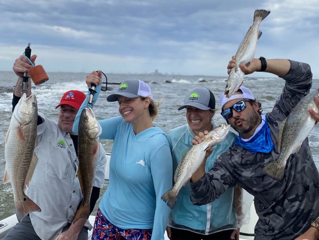 A group of happy friends standing on an inshore fishing charter and posing with their fish caught during around Thanksgiving