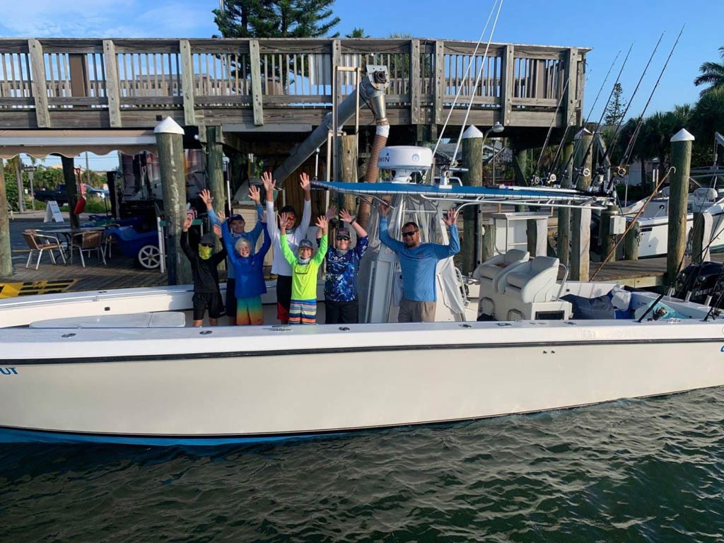 Happy anglers standing on their Madeira Beach fishing charter and holding both hands up in the air to celebrate their successful trip