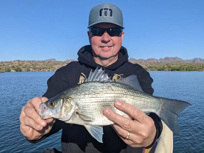 An angler in a hat holding a Panfish caught while fishing in California