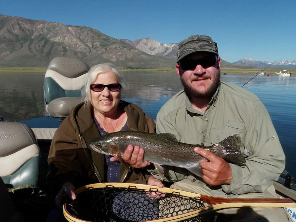 A male and female angler pose with a Rainbow Trout caught while lake fishing in California