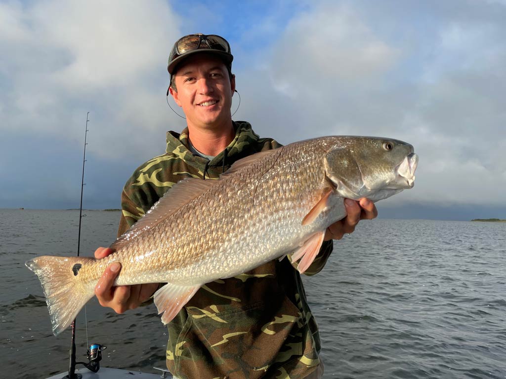 An angler holding a big Redfish he caught fishing in Oregon Inlet.