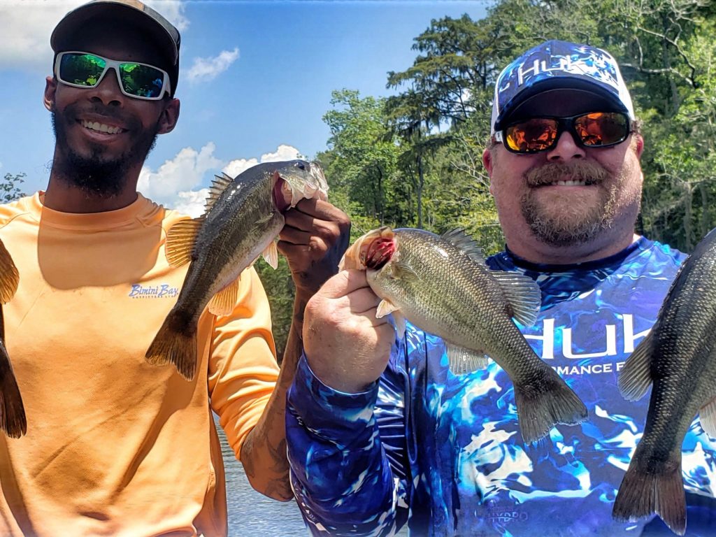 A picture showing two male anglers, each wearing a hat and a pair of sunglasses, smiling and holding two fish each, Murrells Inlet, South Carolina.