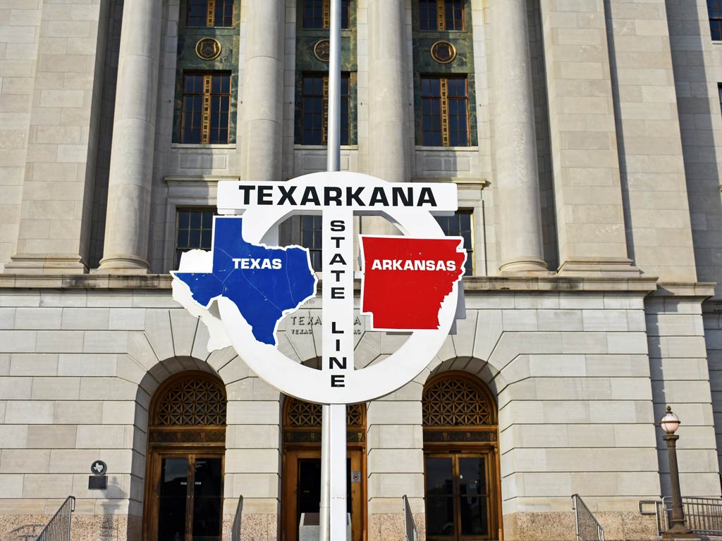 An image of a sign capturing the essence of twin city Texarkana and its state line between Texas and Arkansas