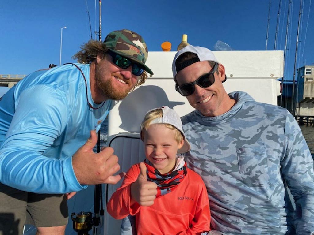 A photo of two anglers and a kid posing on a charter boat