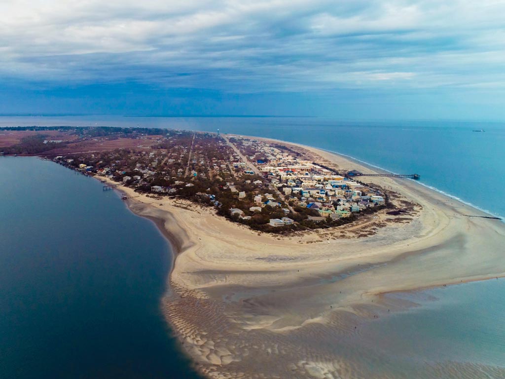 An aerial view of Tybee Island, its beaches, and the calm waters around it on a cloudy day.