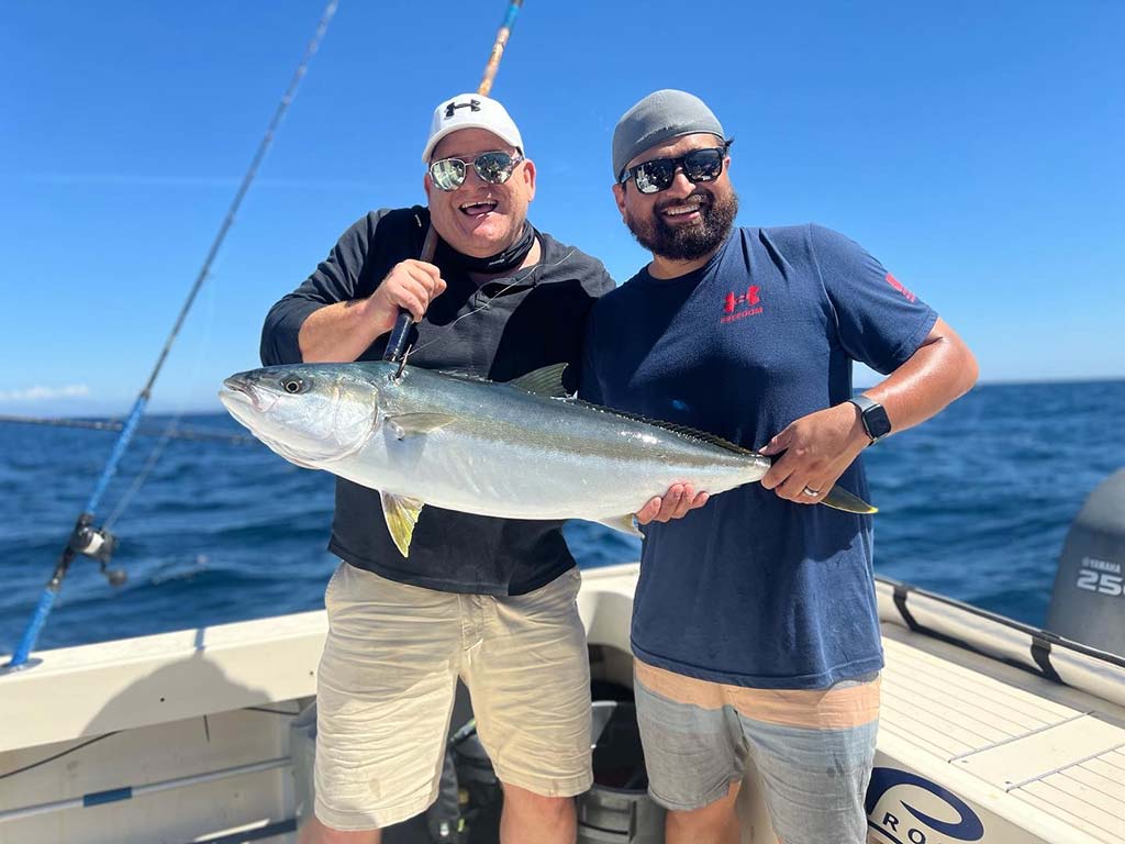 A pair of smiling anglers hold up a Yellowtail Amberjack recently caught on a fishing trip.