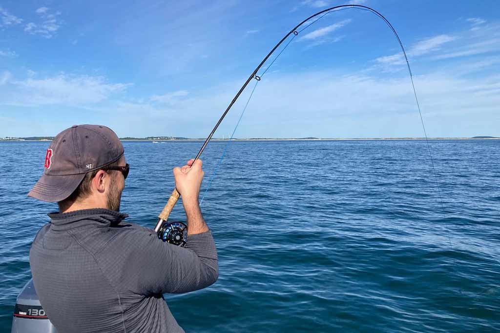 A close-up of an angler holding a bent rod while standing on a boat