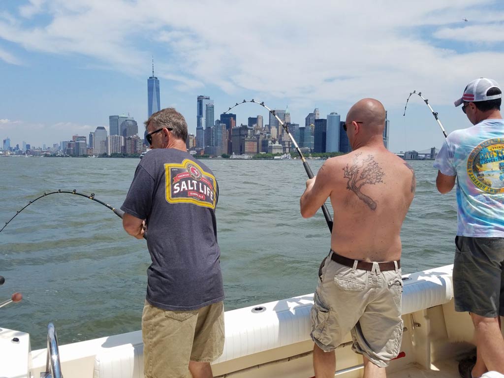 A photo of three anglers facing the city’s skyscrapers while bottom fishing from a NYC charter boat