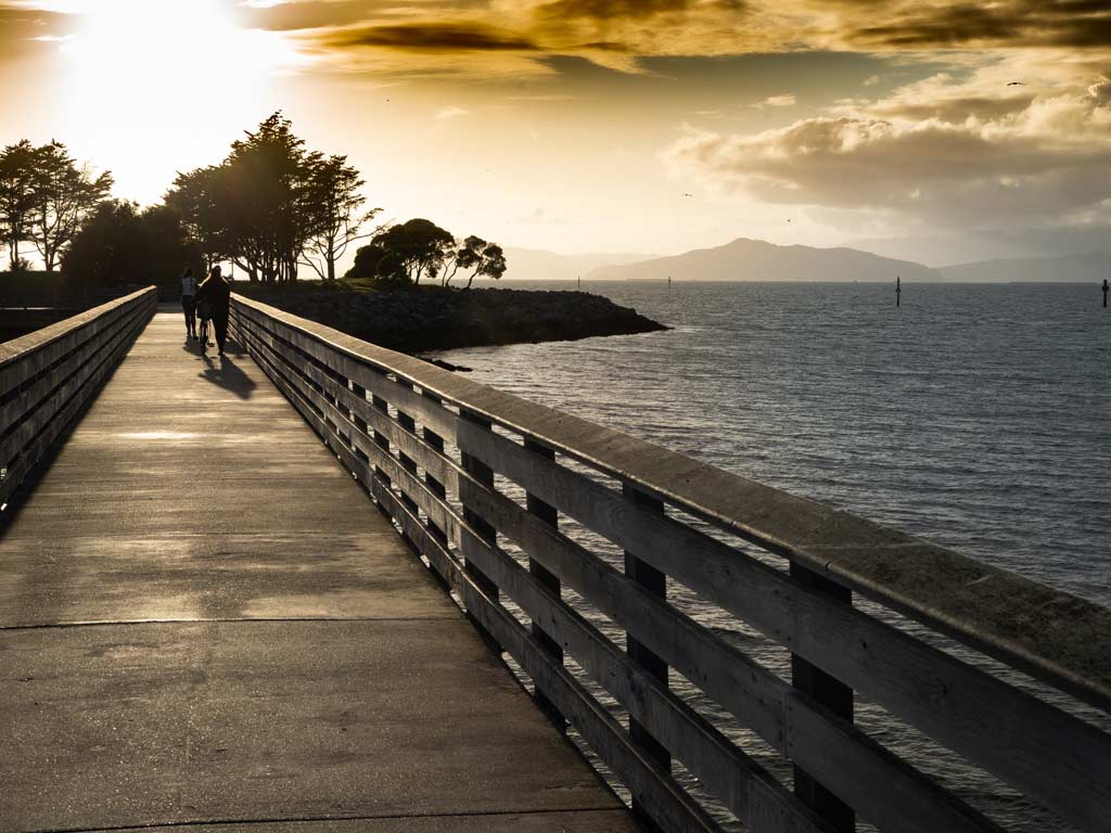 A sunset photo of the Emeryville Pier with waters visible next to it.