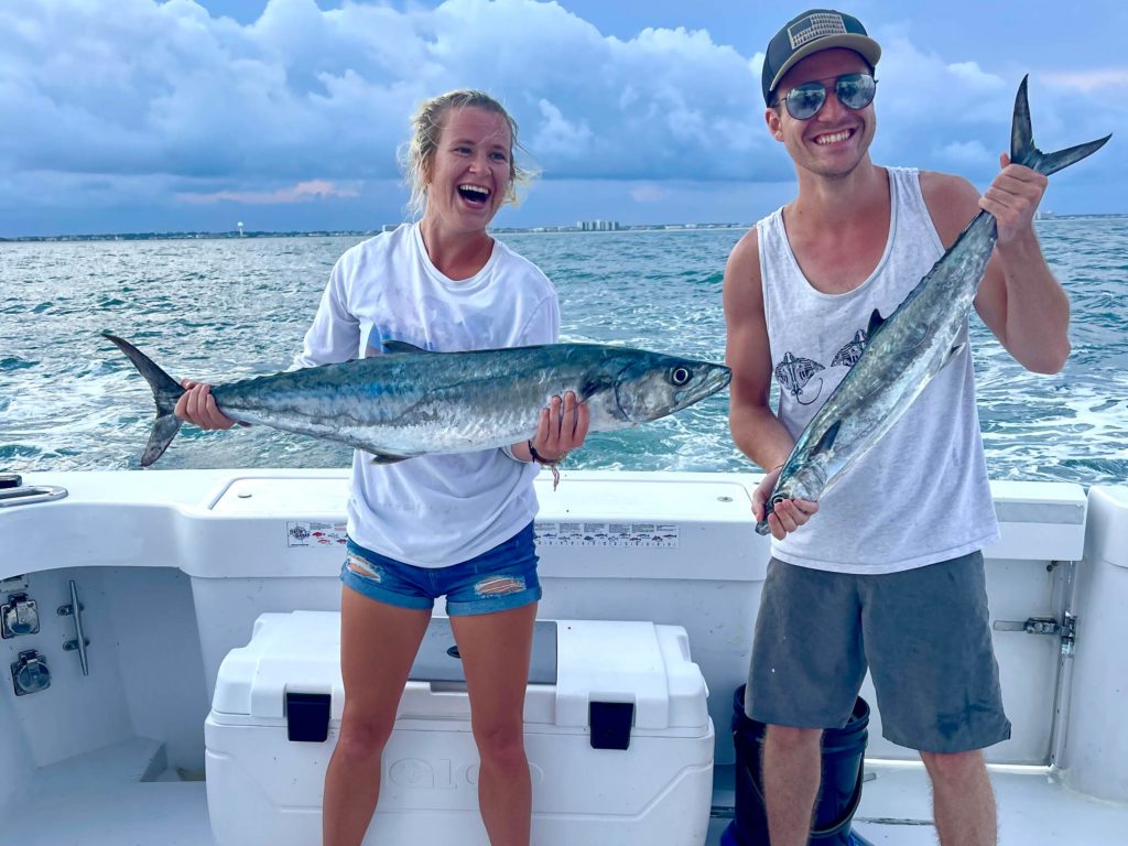 Two happy anglers holding a King Mackerel each caught during an annual King Mackerel run, the Wilmington area, NC