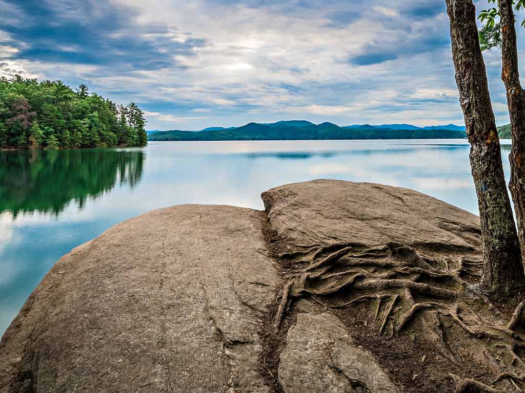 A photo of the pristine Lake Jocassee, with the nearby woods reflecting off the water surface.