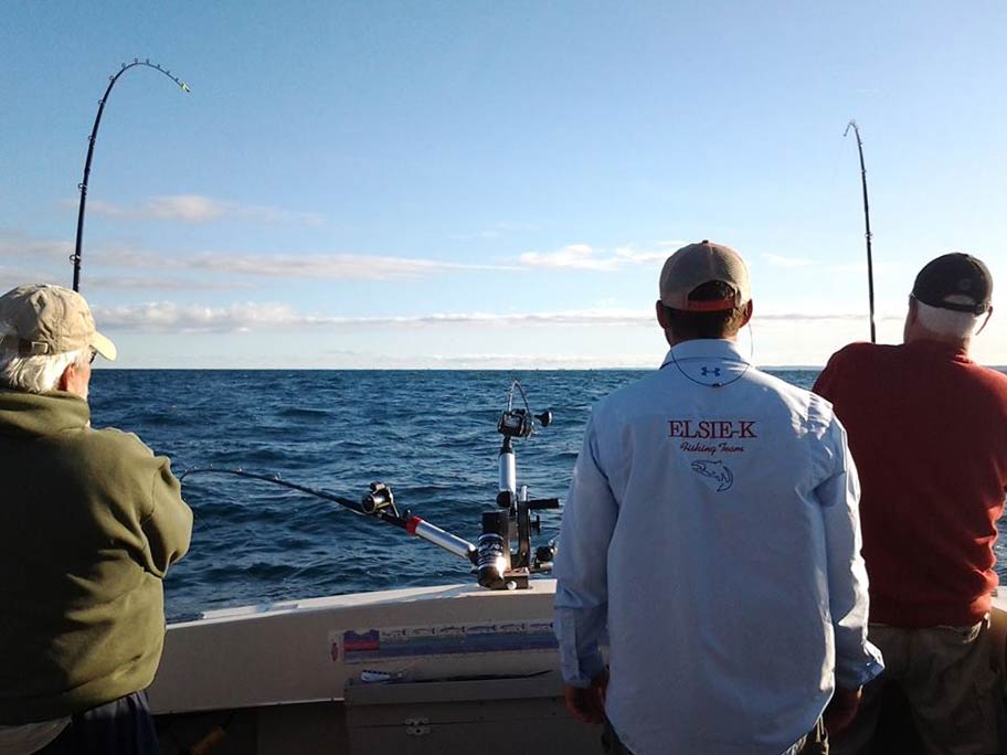 A group of three male anglers fishing on a Great Lake in Michigan, with their backs to the camera