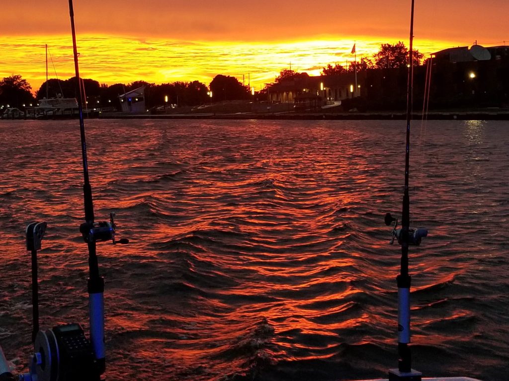 A fishing spot in Michigan at sunset, with fishing rods facing the water