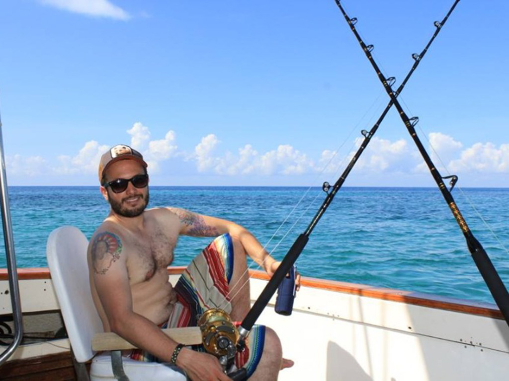 An angler sits on a fighting chair at the back of a boat, getting ready to fish.